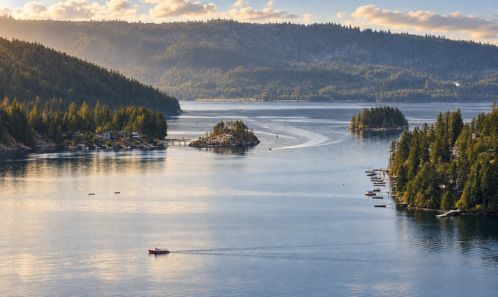 Deep Cove inlet with forested islands, shoreline docks, and a small boat on the water