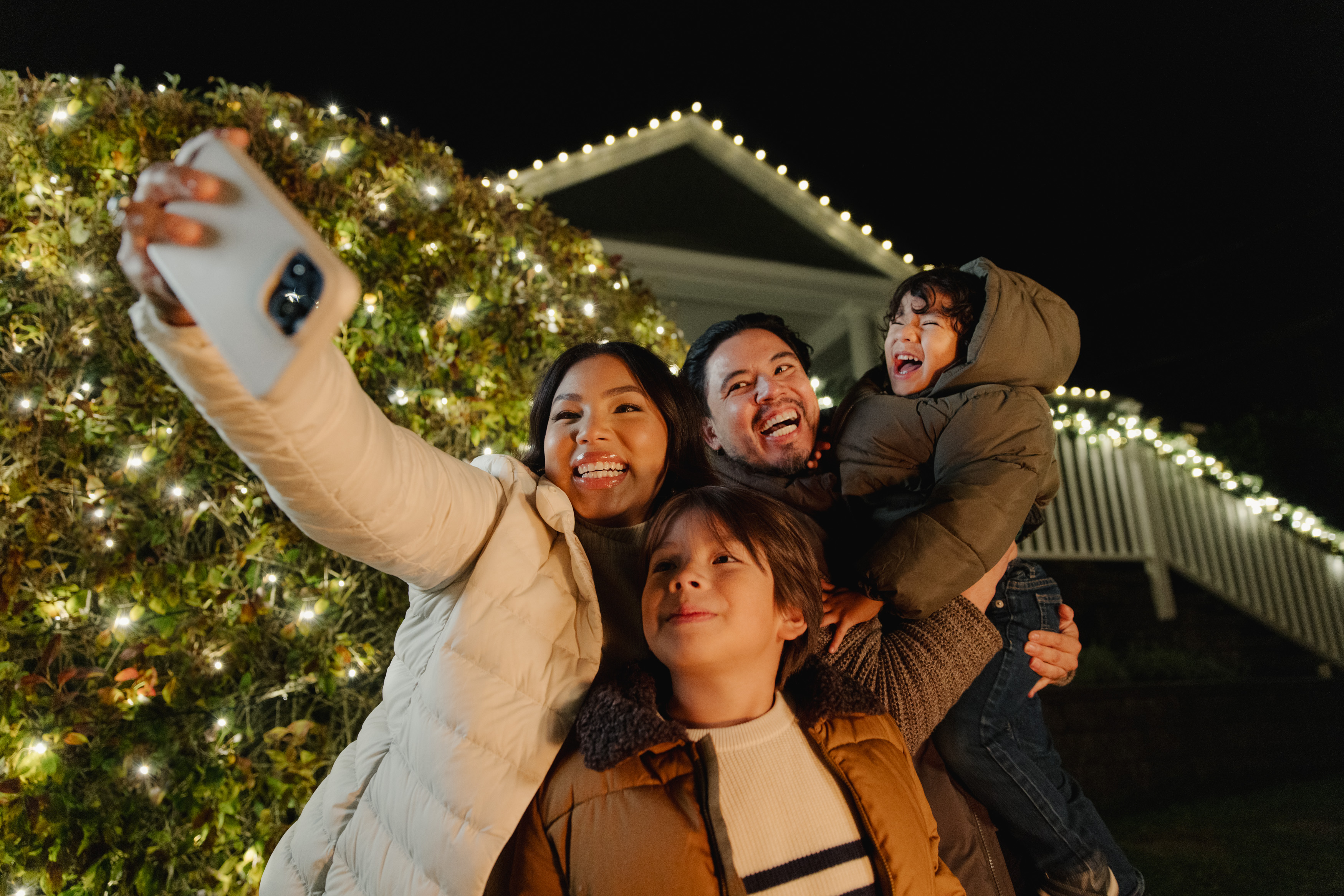 A family taking a selfie in front of their Festilight holiday lighting